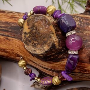 Fioletowa bransoletka na drucie pamięciowym z centralnym koralikiem, złotymi przekładkami z kryształkami oraz muszlowymi kamyczkami, biżuteria handmade