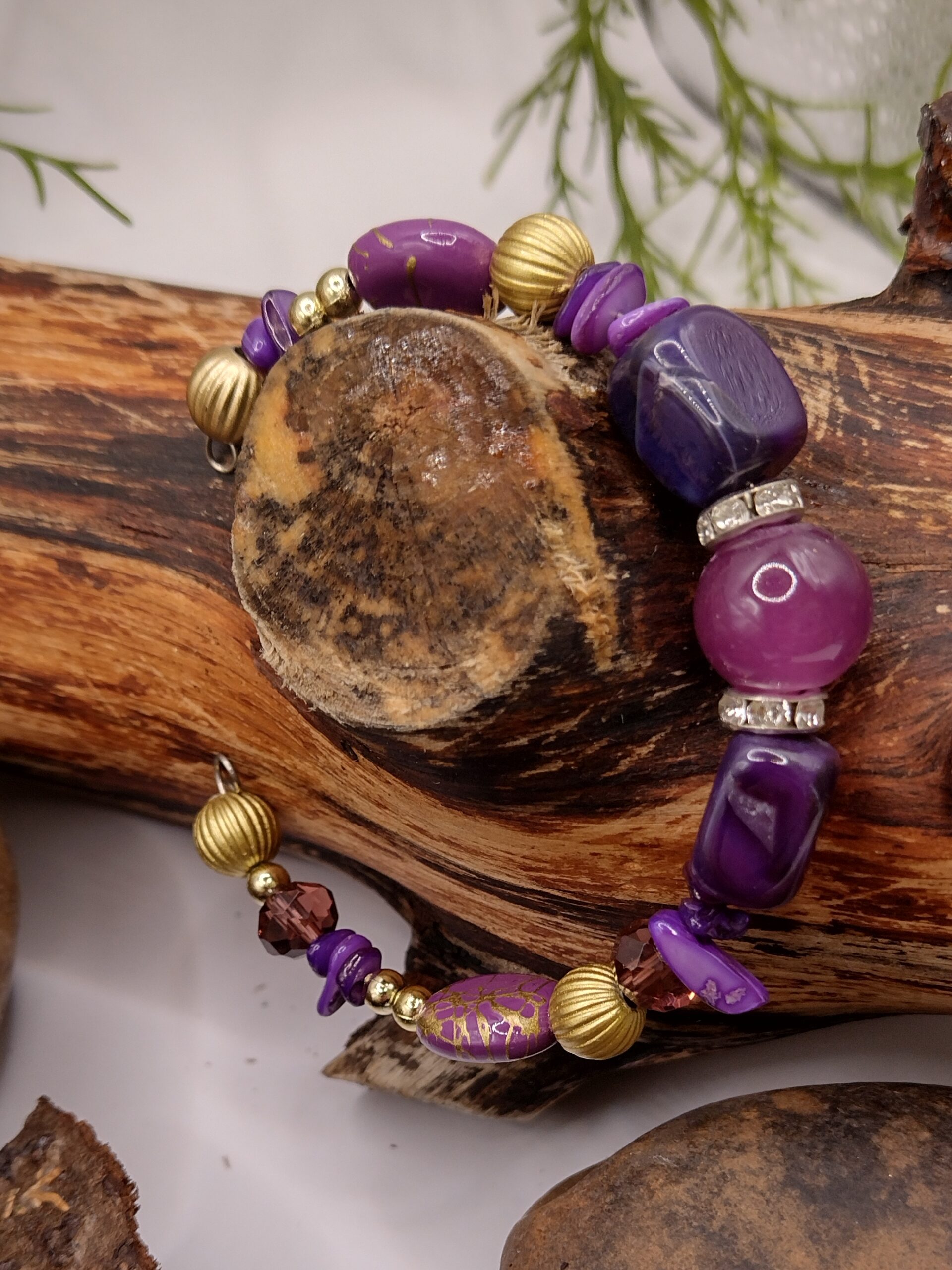 Fioletowa bransoletka na drucie pamięciowym z centralnym koralikiem, złotymi przekładkami z kryształkami oraz muszlowymi kamyczkami, biżuteria handmade