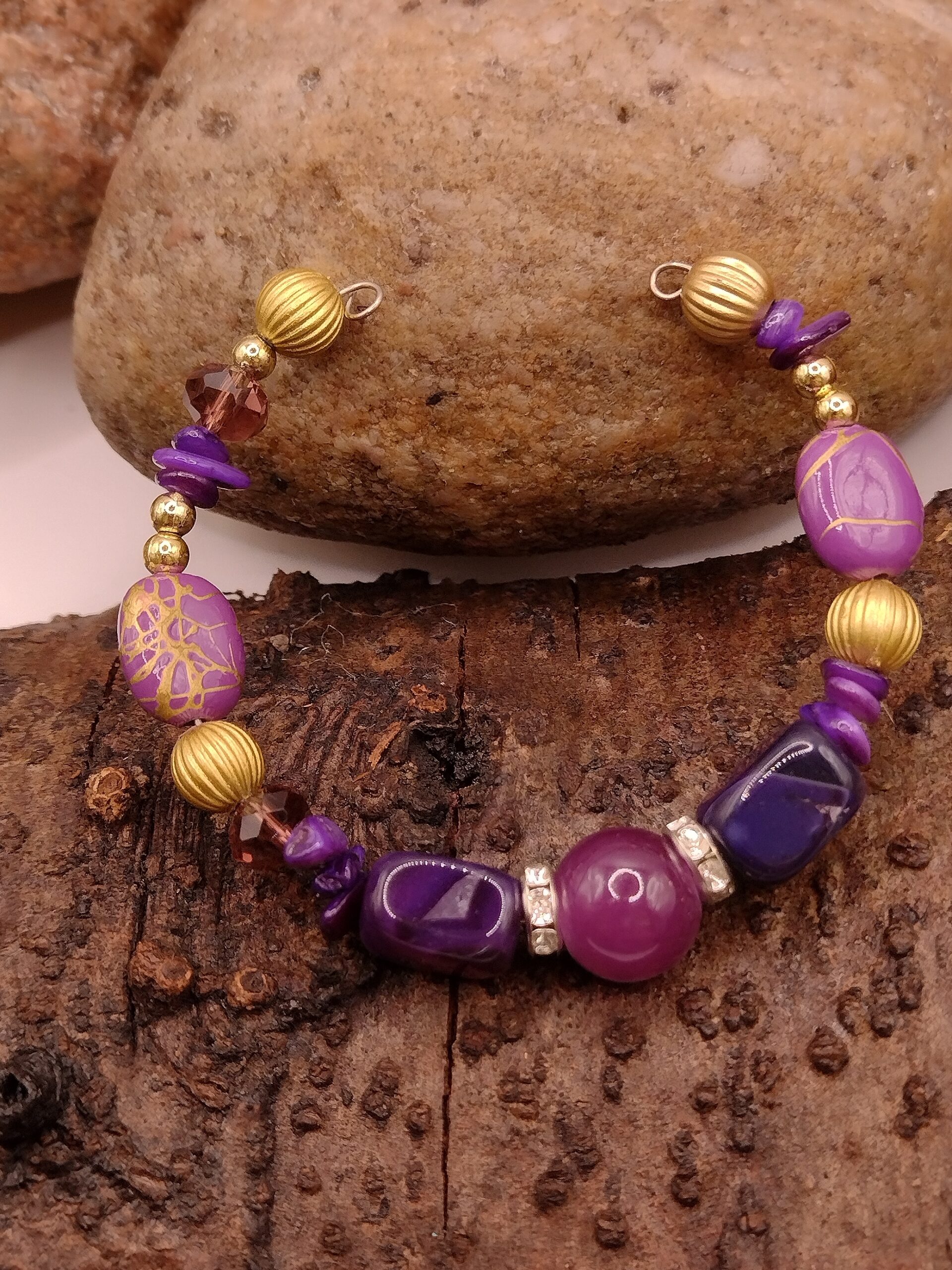 Fioletowa bransoletka na drucie pamięciowym z centralnym koralikiem, złotymi przekładkami z kryształkami oraz muszlowymi kamyczkami, biżuteria handmade