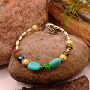 Bransoletka turkusowa na drucie pamięciowym z złotymi koralikami, muszlowymi kamyczkami i dużymi złotymi okrągłymi detalami.