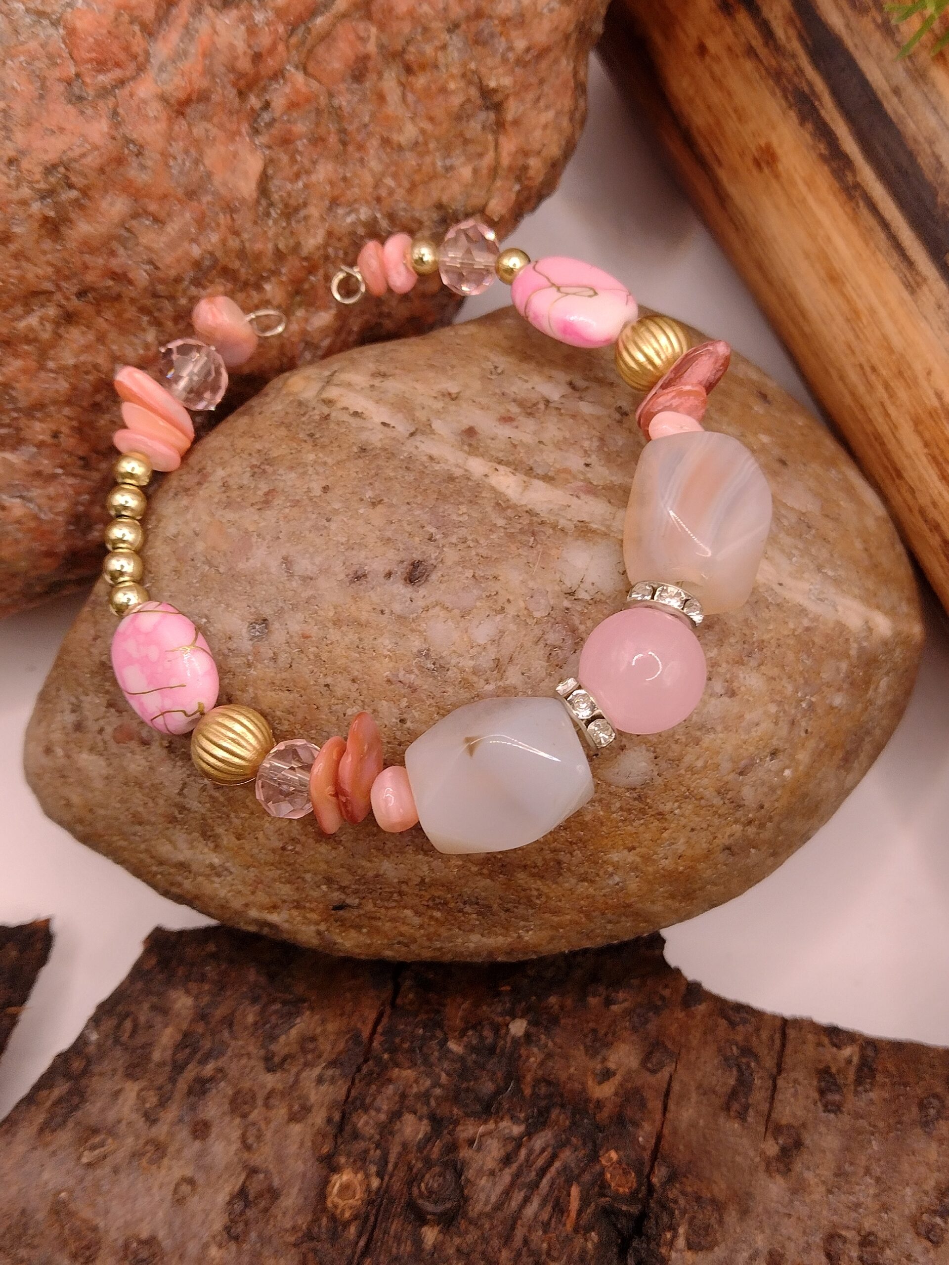 Bransoletka na drucie pamięciowym z jasnoróżowymi i delikatnie ciemniejszymi koralikami, z metalowymi kuleczkami i złotymi przekładkami z kryształkami.