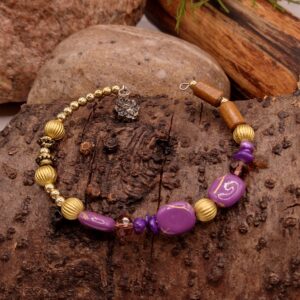 Bransoletka na drucie pamięciowym z fioletowymi koralikami, fioletowymi muszlowymi koralikami, fasetowanymi szklanymi koralikami w odcieniu brązu, z metalowymi złotymi kuleczkami i złotymi przekładkami.