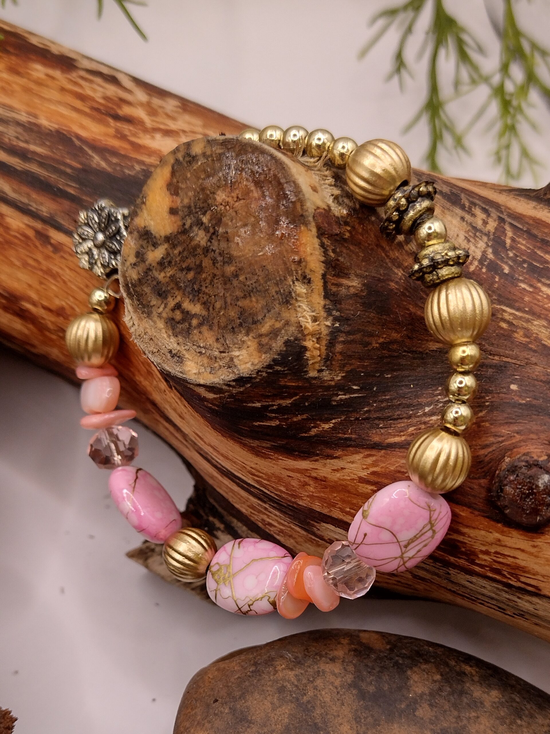 Bransoletka na drucie pamięciowym z jasnoróżowymi i delikatnie ciemniejszymi koralikami, z metalowymi kuleczkami i złotymi przekładkami z kryształkami.