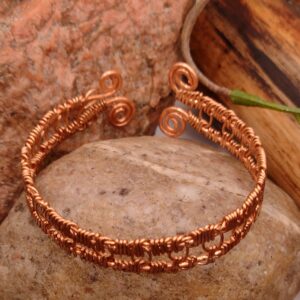 Bransoletka „Spirala Ciszy” z czystej miedzi, ręcznie wykonana, z symetrycznym splotem i spiralnymi zakończeniami, minimalistyczny design.