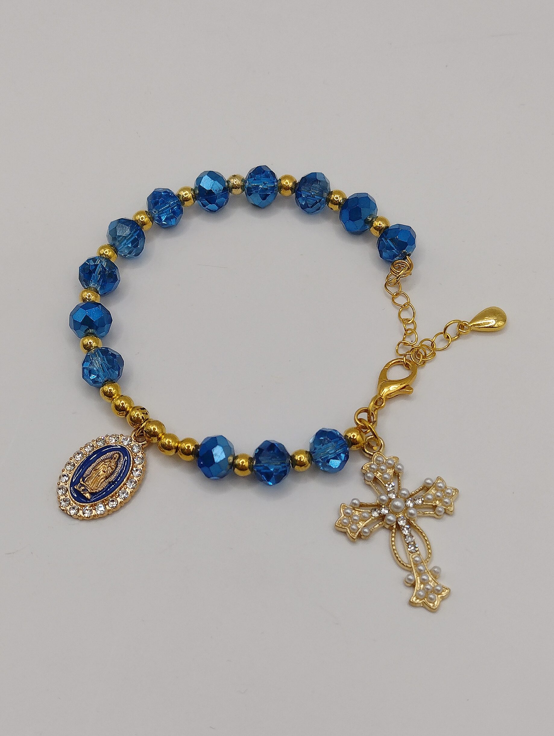 Ręcznie wykonana bransoletka-różaniec z szafirowych fasetowanych koralików i złotych akcentów, z ozdobnym krzyżykiem oraz medalikiem Matki Boskiej na regulowanym zapięciu.