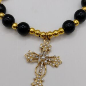 Bransoletka‑różaniec „Modlitwa Ochrony” z czarnych perełek, z medalikiem Jezusa i ozdobnym krzyżykiem.