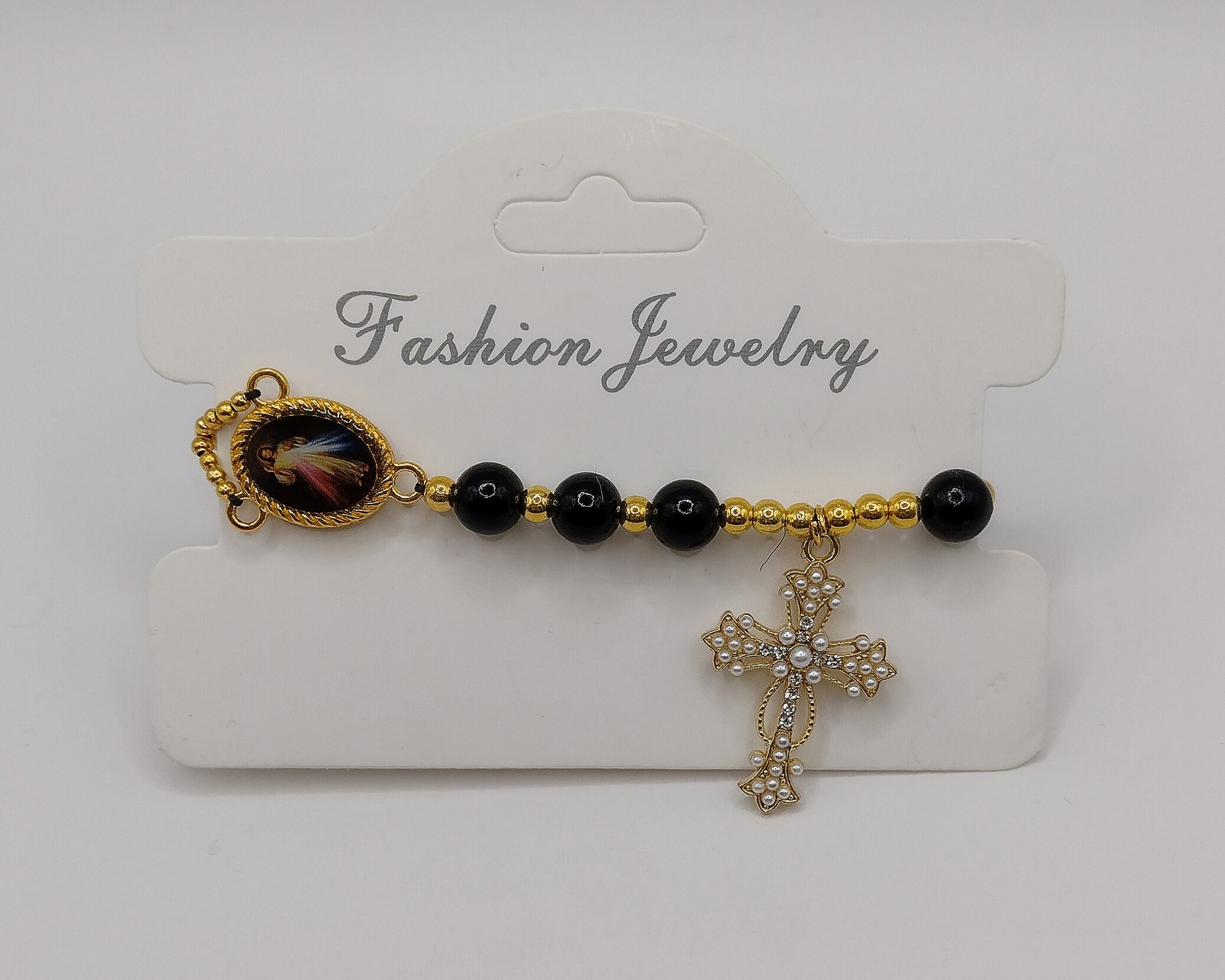 Bransoletka‑różaniec „Modlitwa Ochrony” z czarnych perełek, z medalikiem Jezusa i ozdobnym krzyżykiem.