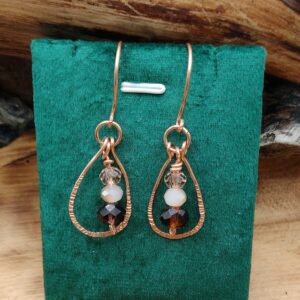 Kolczyki z miedzianą ramą i fasetowanymi koralikami w ciepłych odcieniach kremu i brązu.