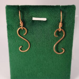 Ręcznie wykonane miedziane kolczyki o falującej formie ze spiralnym detalem.