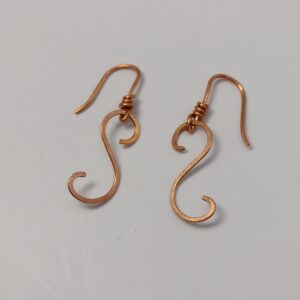 Ręcznie wykonane miedziane kolczyki o falującej formie ze spiralnym detalem.