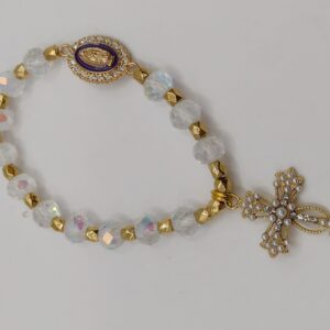 Bransoletka‑różaniec z białych fasetowanych koralików na elastycznej gumce, z ozdobnym krzyżykiem i medalikiem Matki Boskiej.