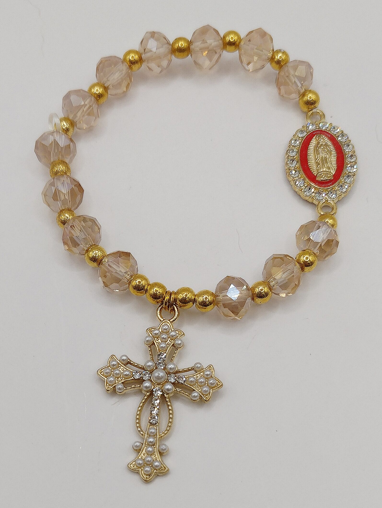 Bransoletka‑różaniec z białych fasetowanych koralików na gumce, z ozdobnym krzyżykiem i medalikiem Matki Boskie