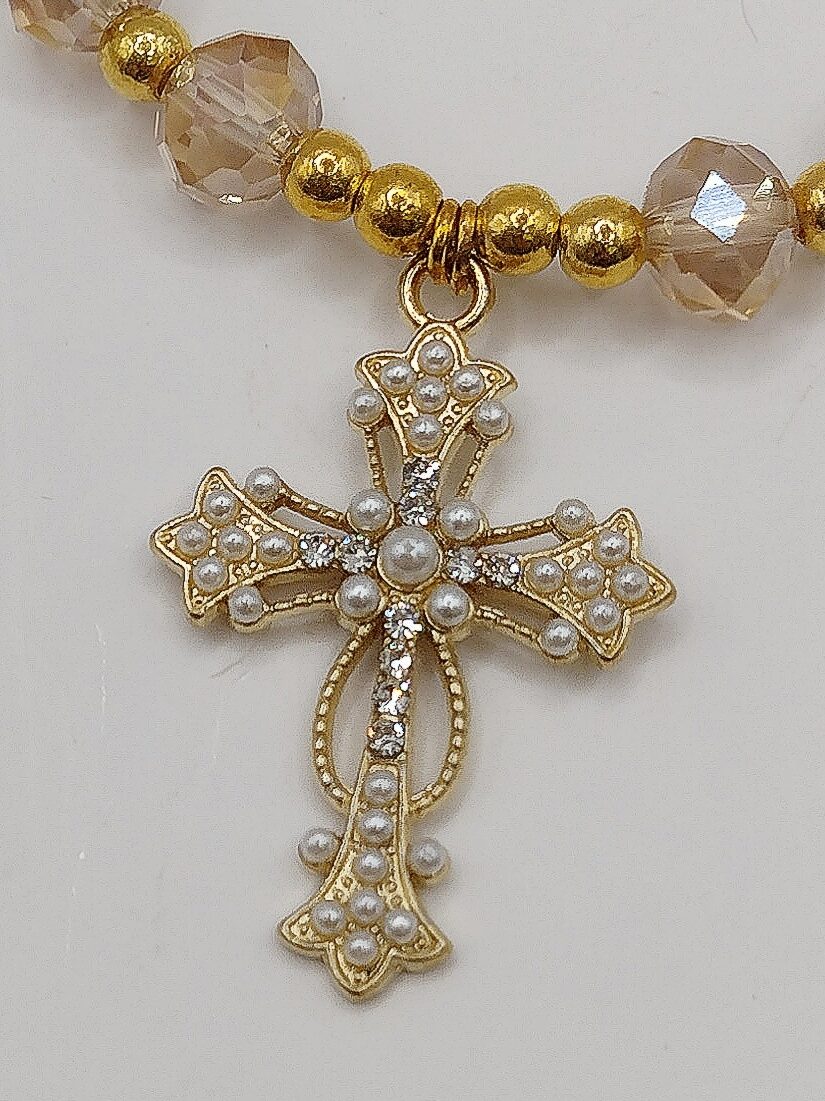 Bransoletka‑różaniec z białych fasetowanych koralików na gumce, z ozdobnym krzyżykiem i medalikiem Matki Boskiej